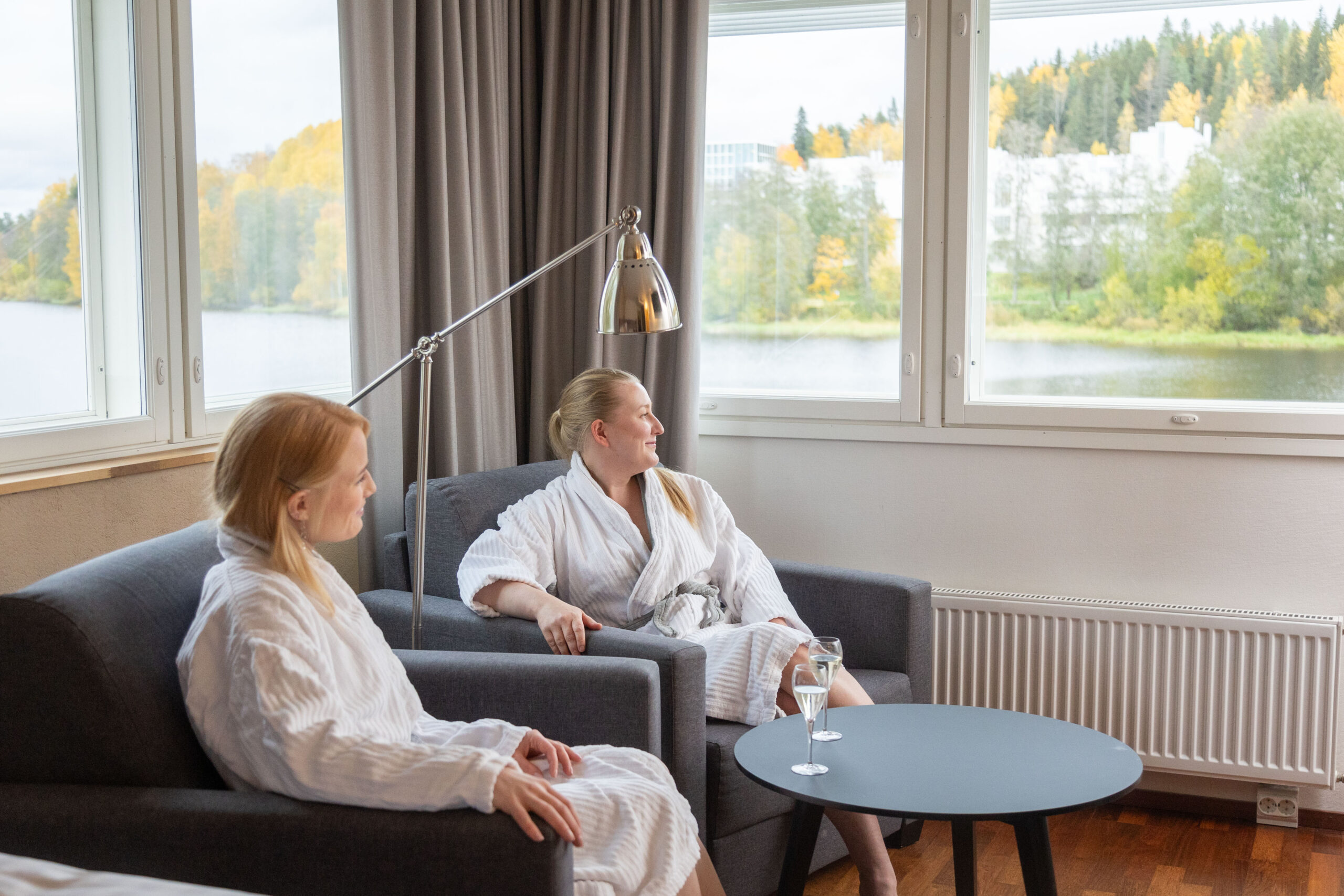 Kaksi naista kylpytakeissa katselee maisemaa hotellihuoneesta