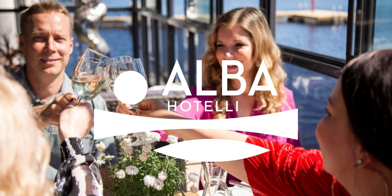 Iloisia ihmisiä terassilla järven rannalla kohottamassa maljaa