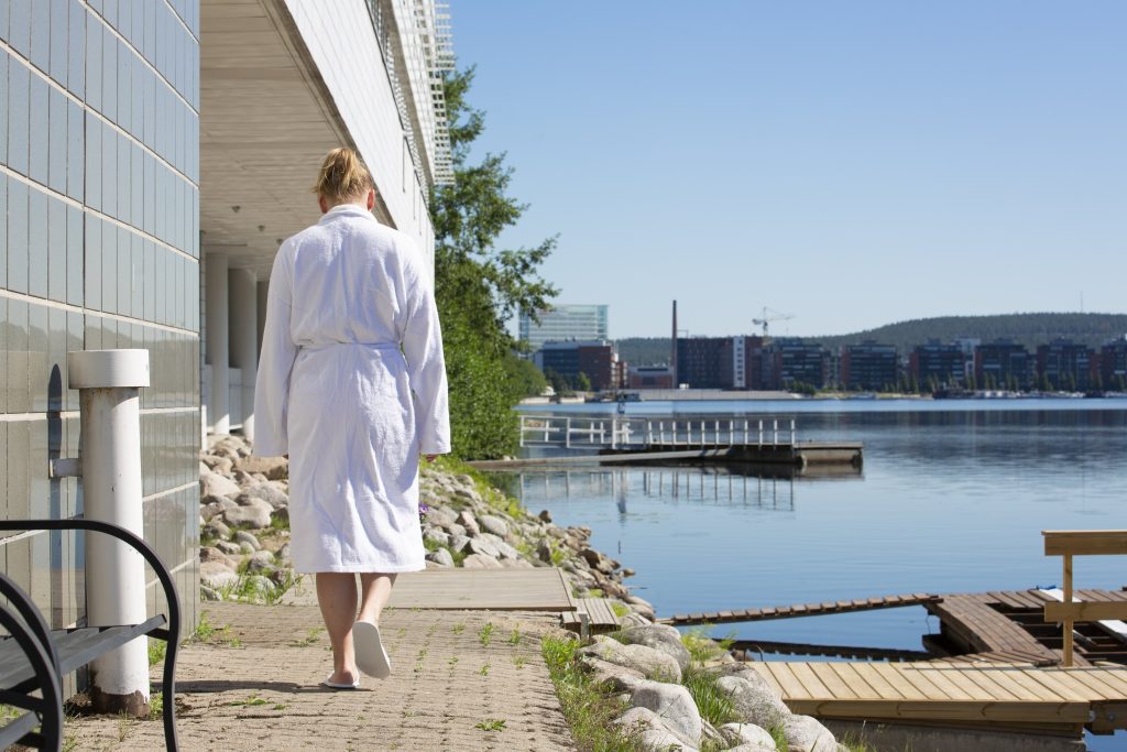 Nainen kävelemässä kylpytakki päällä laiturille