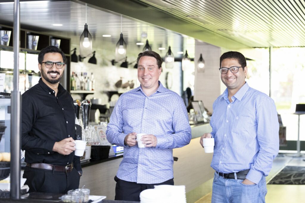 Kolme miestä kokoustamassa Jyväskylässä kahvikupit kädessä