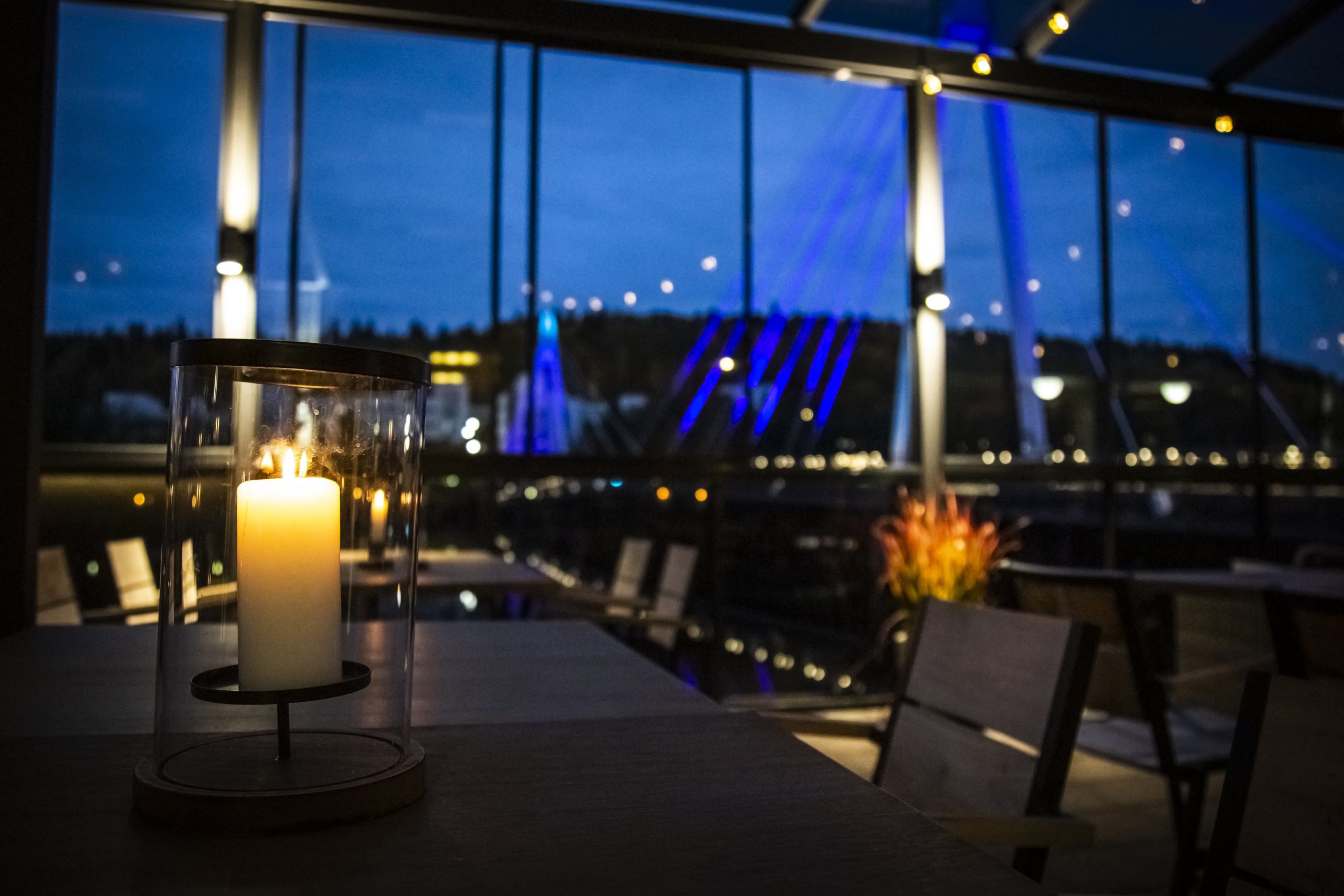 Kuva kynttilästä Alban terassin pöydällä. Kuvan taustalla näkyy Ylistön silta.