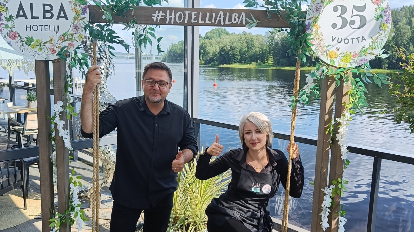 Mies ja nainen hymyilee iloisesti järven rannalla terassilla Jyväskylässä